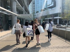 Shoppers carry full bags from the Friends and Family Day of the Aritzia Warehouse Sale in Vancouver on Aug. 28, 2023.