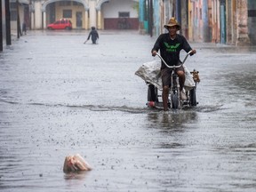 A man rides a tricycle through a flooded street in Havana, on Augusto 29, 2023, during the passage of tropical storm Idalia. Tropical Storm Idalia strengthened into a hurricane this Tuesday and forecasters are forecasting it to become "extremely dangerous" before making landfall on Wednesday in Florida, US.
