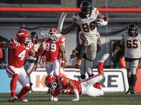 B.C. Lions wide receiver Jevon Cottoy, centre, leaps over Calgary Stampeders defensive back Branden Dozier during CFL game in Calgary, Thursday, June 8, 2023.