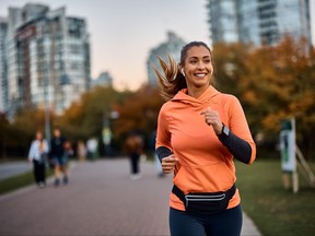 Happy sportswoman with earbuds running in the park.