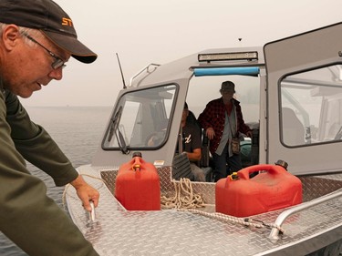 Corey Rasmussen (L) loads a boat to bring supplies across Shuswap Lake to high alert and evacuated areas that don't have road access as the Bush Creek East fire continues to burn in Blind Bay, British Columbia, August 21, 2023. Around 30,000 people were under orders from August 19 to evacuate their homes in western Canada's British Columbia, provincial officials said, as a raging wildfire bore down on the city of Kelowna. (Photo by Paige Taylor White / AFP)