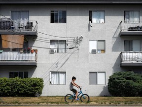 Window mounted air conditioners and exhaust hoses from portable units are seen in apartment windows, in Burnaby, B.C., on Saturday, August 5, 2023.