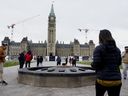 Visitors and tourists to Parliament Hill stand around the Centennial flame on Parliament Hill in Ottawa on Friday, Oct. 22, 2021. China lifted a pandemic ban on group tours to several countries, including the United States and Australia, but tourists are still be barred from group visits to Canada.