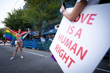 A person poses for a picture in the street during the Pride Parade at English Bay in Vancouver, B.C., Sunday, Aug. 6, 2023.