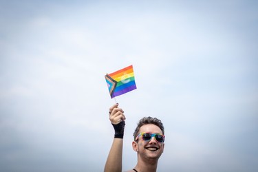 A person is seen waving a pride flag during the Pride Parade at English Bay in Vancouver, B.C., Sunday, Aug. 6, 2023.