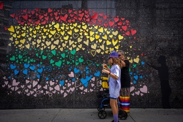 People pass a decorated wall during the Pride Parade at English Bay in Vancouver, B.C., Sunday, Aug. 6, 2023.