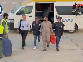 In this image taken from a video and released by the Italian Carabinieri on Thursday, Aug. 31, 2023, Shabbir Abbas, at center with mustaches, a Pakistani man who is currently being tried in Italy for the murder of his daughter after she refused a forced marriage, is escorted by Italian Carabinieri to the flight that will bring him back to Italy from an undisclosed location in Pakistan.