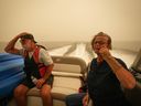 Smoke fills the air as Trevor Manzuik and his wife Pat are given a boat ride by good samaritan Christy Dewalt, not seen, back to their home they  were evacuated from due to the Lower East Adams Lake wildfire, in  Scotch Creek, B.C., Sunday, Aug. 20, 2023. 