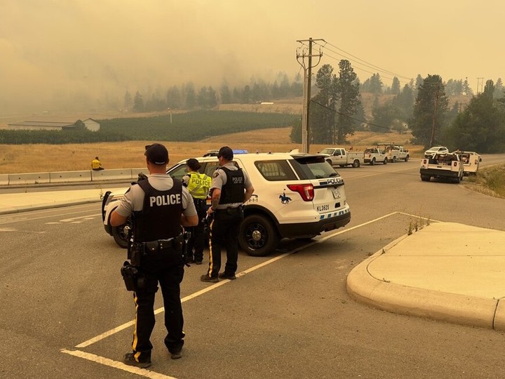  File photo of RCMP officers watching smoke billowing from a wildfire at a police checkpoint.