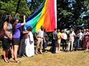 City councillors, activists and guests raise a Pride flag at City Hall on Monday.