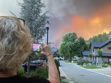Wendy Creelman taking photos of the West Kelowna wildfire Thursday night from in front of her house in Kelowna's Glenmore Highlands, not long before she and her daughter Alexa, visiting from Vancouver, were forced to flee after the fire jumped Okanagan Lake.