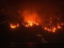 The McDougall Creek wildfire burns on the mountainside above a lakefront home, in West Kelowna, B.C., on Friday, Aug. 18, 2023. 