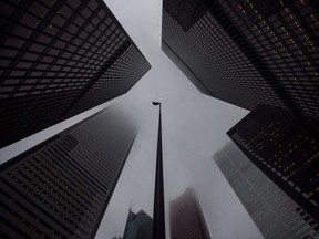 A Canadian flag blows in the wind between bank towers in the heart of Toronto's financial district.