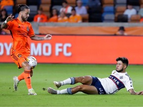 Vancouver Whitecaps midfielder Ryan Raposo, right, slide-tackles Houston Dynamo midfielder Sebastian Kowalczyk, who is struck by the ball during the first half of an MLS soccer match Wednesday, Sept. 20, 2023, in Houston.
