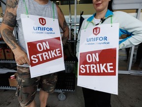 Workers hold signs at a picket line outside a Metro grocery store in Toronto, Saturday, July 29, 2023.