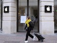 FILE: A woman walks past a closed Apple Store in Lille, northern France, Monday, March 16, 2020.