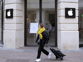 FILE: A woman walks past a closed Apple Store in Lille, northern France, Monday, March 16, 2020.