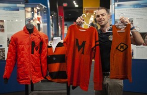 Vancouver, BC: September08, 2023 --BC Sports Hall of Fame curator and facility director Jason Beck with Meraloma Club jerseys at the museum Friday, September 8, 2023. The club is a BC sports institution and is celebrating its first century. Pictured left to right; Eric Cameron winter jacket, striped rugby jersey from the 1960's, jersey from the 1930's and a track and field or swimming jerseyn from the 1920's. (Photo by Jason Payne/ PNG) (For story by Dan Fumano) [PNG Merlin Archive]