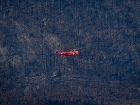 A helicopter being used to battle hot spots near Sorrento lands in Squilax, B.C., Wednesday, Sept. 6, 2023, as trees burned by the Bush Creek East wildfire are seen on a mountainside. The British Columbia Wildfire Service says the fire danger rating across most of the province has dropped to low or very low as cool, damp fall weather arrives.