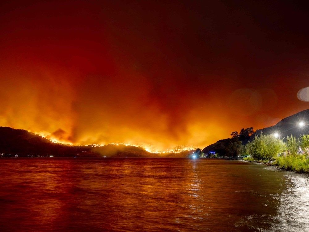 (Residents watch the McDougall Creek wildfire in West Kelowna, British Columbia, Canada, on Aug. 17, 2023, from Kelowna. (Photo by Darren HULL / AFP) (Residents watch the McDougall Creek wildfire in West Kelowna, British Columbia, Canada, on Aug. 17, 2023, from Kelowna. (Photo by Darren HULL / AFP)