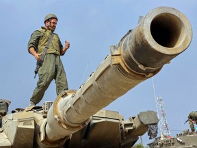 A soldier stands on the turret of a tank as Israeli forces take positions near the border with Gaza on Oct. 11.