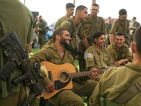 Israeli soldiers relax at a staging area near the Gaza Strip, in southern Israel Monday.