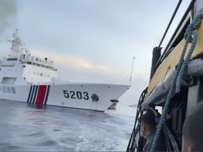 In this image from a video released by the Armed Forces of the Philippines, Filipino sailors look on after a Chinese coast guard ship bumps their supply boat as they approach Second Thomas Shoal, locally called Ayungin Shoal, in the disputed South China Sea on Sunday.