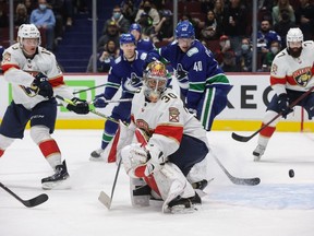 Florida Panthers goalie Spencer Knight watches as the puck deflects off the post behind him as Anton Lundell, left, defends against Vancouver Canucks' Elias Pettersson.