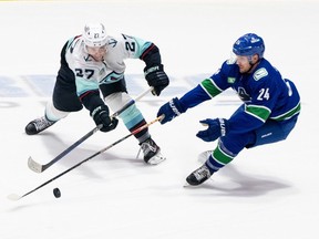 Seattle Kraken's Cale Fleury (27) tries to pass the puck as Vancouver Canucks' Pius Suter (24) defends during the third period of preseason NHL action in Abbotsford, B.C. on Wednesday, Oct. 4, 2023.