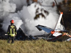A firefighter stands near a small plane that crashed