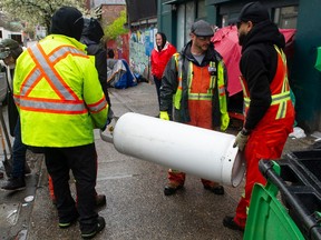 City workers remove a 100-pound capacity propane tank as the city evicted campers from three blocks of East Hasting in April.