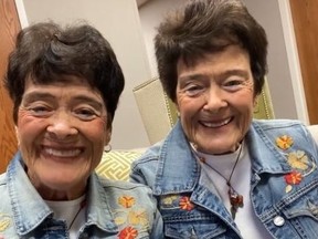 Twin sisters Anne McQueen and Susan Briggs, wearing wearing matching jean outfits.
