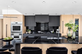 The black recessed centre-stack of the hood fan and cooktop provide a visual focal point while the warm-toned, white-oak tower cabinets framing it keep the space light.
