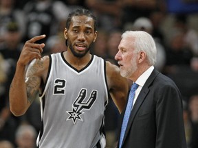 Kawhi Leonard of the San Antonio Spurs talks with head coach Gregg Popovich on March 12, 2016 in San Antonio, Texas.