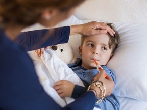 A mother checks the temperature of her sick son.