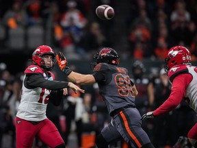 Calgary Stampeders quarterback Jake Maier, left, passes while under pressure from B.C. Lions' Mathieu Betts (90) during the 2022 CFL Western Semifinal at B.C. Place.