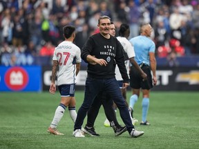 Vancouver Whitecaps head coach Vanni Sartini is restrained by a member of the team's staff after he went on the field and tried to get to referee Tim Ford after he received a red card during the second half in game 2 of a first round MLS playoff soccer match against Los Angeles FC.