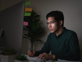 A young man sits at desk working late into the night.