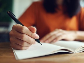 A woman handwriting in a notebook.