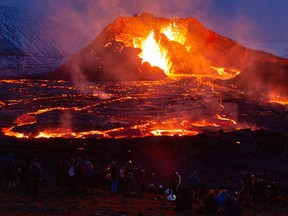 MARCH 28: People's figures are illuminated by the glow of the lava on March 28, 2021 on the Reykjanes Peninsula, Iceland.