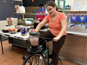 Breakfast volunteer Alivia Wells taking the pedal-powered smoothie maker for a spin at King George Secondary.