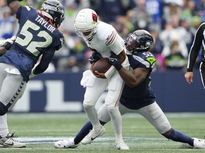 Arizona Cardinals quarterback Joshua Dobbs, center, gets taken down by Seattle Seahawks linebacker Boye Mafe (53) as Seahawks linebacker Darrell Taylor (52) arrives to join in on the tackle during the second half of an NFL football game Sunday, Oct. 22, 2023, in Seattle.