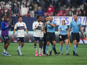 Referee Tim Ford (centre right) is followed by Vancouver Whitecaps' Ali Ahmed (centre left) and (Sam Adekugbe, back left) as he leaves the field after Los Angeles FC defeated the Vancouver Whitecaps during Game 2 of a first round MLS playoff soccer match, in Vancouver, on Sunday, Nov. 5, 2023.