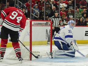 Chicago Blackhawks right wing Corey Perry, left, scores against Tampa Bay Lightning goaltender Jonas Johansson, right, during the third period of an NHL hockey game Thursday, Nov. 16, 2023, in Chicago.