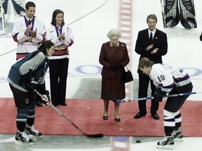 Markus Naslund (z prawej) z Vancouver Canucks podnosi krążek po tym, jak królowa Elżbieta II upuściła krążek podczas uroczystego wznowienia pomiędzy Naslund a Mikiem Ritchie z San Jose Sharks w General Motors Place w Vancouver w Kolumbii Brytyjskiej, niedziela, 6 października 2002 r. .