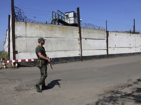 FILE - A soldier stands guard next to a wall of a prison in Olenivka, in an area controlled by Russian-backed separatist forces, eastern Ukraine, July 29, 2022. A Russian news agency is reporting that the country is preparing to send a battalion of Ukrainian prisoners of war to the front lines in their homeland to fight on Moscow's side in the war. The Associated Press could not immediately confirm the authenticity of the report or if the POWs were coerced. (AP Photo, File)