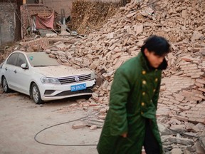 TOPSHOT - A man walks past a collapsed house in Dahejia in Jishishan County in northwest China's Gansu province on December 20, 2023. Survivors of China's deadliest earthquake in years huddled in aid tents on December 20 after overnight temperatures plunged well below zero, with the death toll rising to 149.