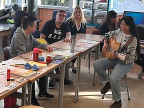 Music therapist Taylor Tabernero plays for Sandra Perrotta's class in Burnaby Central Secondary, Friday. It takes a month of collecting bottles and cans for Perrotta (second left of Tabernero) to raise the money to pay for therapy. Photo by James Liu.
