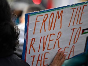A demonstrator displays a placard with the lettering 'From the river to the sea' during a rally in solidarity with Palestinians at Oranienplatz Square in Berlin's Kreuzberg district, Germany, on November 11, 2023.