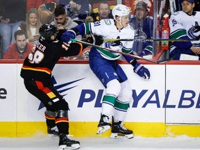Vancouver Canucks defenceman Nikita Zadorov (right) swats away a check from Calgary Flames forward A.J. Greer during first period NHL hockey action in Calgary on Dec. 2, 2023.